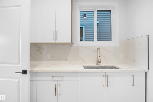Bar area featuring white cabinets, light stone counters, tasteful backsplash, and modern cabinets - 6228 29 Avenue, Edmonton, AB - Indoor Photo Showing Kitchen With Double Sink