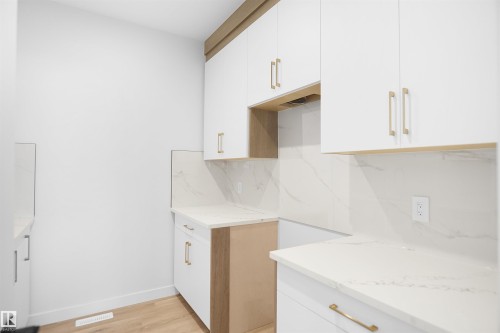 Kitchen featuring white cabinetry, light wood-style flooring, tasteful backsplash, and light stone countertops - 6228 29 Avenue, Edmonton, AB - Indoor Photo Showing Other Room