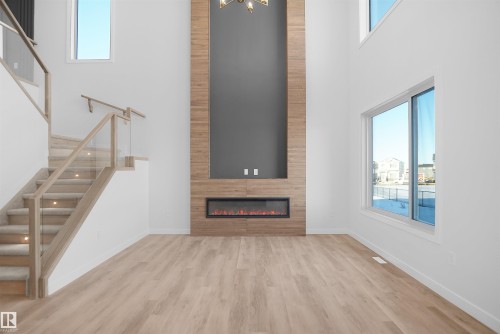 Unfurnished living room with a high ceiling, wood finished floors, a fireplace, and a chandelier - 6228 29 Avenue, Edmonton, AB - Indoor Photo Showing Other Room With Fireplace