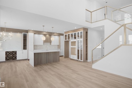 Two tone kitchen with two tone cabinetry, light countertops, glass insert cabinets, a kitchen island with sink, and light wood-type flooring - 6228 29 Avenue, Edmonton, AB - Indoor Photo Showing Other Room