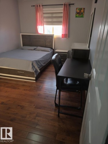 Bedroom featuring dark wood-style floors - 4 4350 23 Street, Edmonton, AB - Indoor Photo Showing Bedroom