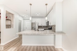 Kitchen featuring tasteful backsplash, white cabinetry, a peninsula, stainless steel appliances, and light wood-style floors - 