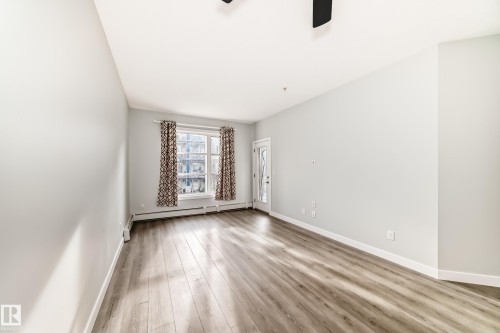 Spare room featuring light wood-type flooring, a ceiling fan, and baseboard heating - 201 2588 Anderson Way, Edmonton, AB - Indoor Photo Showing Other Room