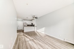 Unfurnished living room featuring light wood finished floors, ceiling fan, and baseboard heating - 