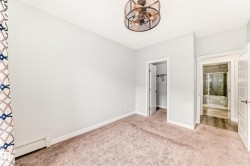 Unfurnished bedroom with a spacious closet, baseboard heating, and light carpet - 