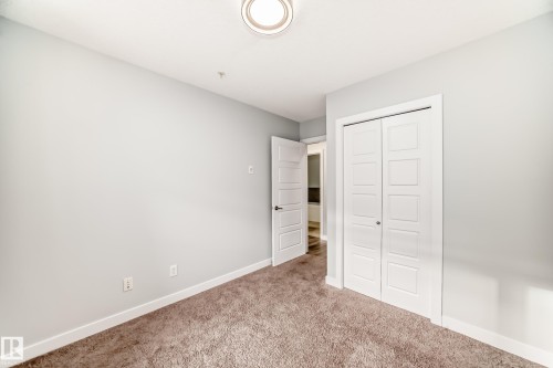 Unfurnished bedroom with a closet and carpet floors - 201 2588 Anderson Way, Edmonton, AB - Indoor Photo Showing Other Room