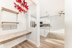 Kitchen with a breakfast bar area, white cabinets, light wood-type flooring, hanging light fixtures, and stainless steel appliances - 