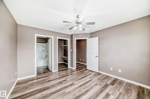 Unfurnished bedroom with ensuite bathroom, a walk in closet, light wood-type flooring, and a ceiling fan - 9332 211 Street Nw, Edmonton, AB - Indoor Photo Showing Other Room
