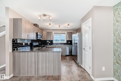 Kitchen with stainless steel appliances, a peninsula, backsplash, and modern cabinets - 9332 211 Street Nw, Edmonton, AB - Indoor Photo Showing Kitchen