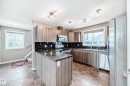 Kitchen with stainless steel appliances, a peninsula, backsplash, dark countertops, and a textured ceiling - 9332 211 Street Nw, Edmonton, AB  - Indoor Photo Showing Kitchen With Double Sink 