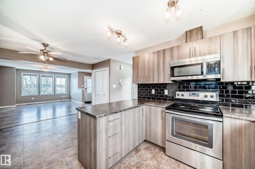 Kitchen with stainless steel appliances, ceiling fan, a peninsula, open floor plan, and backsplash - 9332 211 Street Nw, Edmonton, AB - Indoor Photo Showing Kitchen With Stainless Steel Kitchen