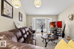 Carpeted living area with a textured ceiling and baseboards - 