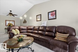 Carpeted living area featuring a ceiling fan and lofted ceiling - 