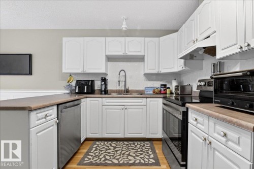 Kitchen featuring electric stove, a peninsula, white cabinetry, dishwasher, and a textured ceiling - 13217 155 Avenue Nw, Edmonton, AB - Indoor Photo Showing Kitchen