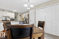 Kitchen with white cabinets, stainless steel appliances, tasteful backsplash, light countertops, and hanging lights - 