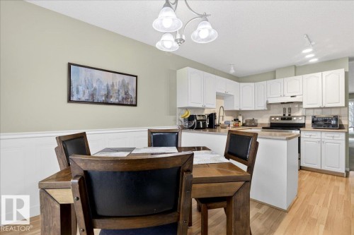Kitchen featuring white cabinetry, light wood-style floors, a peninsula, wainscoting, and decorative backsplash - 13217 155 Avenue Nw, Edmonton, AB - Indoor