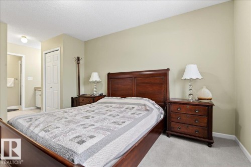 Bedroom featuring a closet, light colored carpet, a textured ceiling, and ensuite bathroom - 13217 155 Avenue Nw, Edmonton, AB - Indoor Photo Showing Bedroom