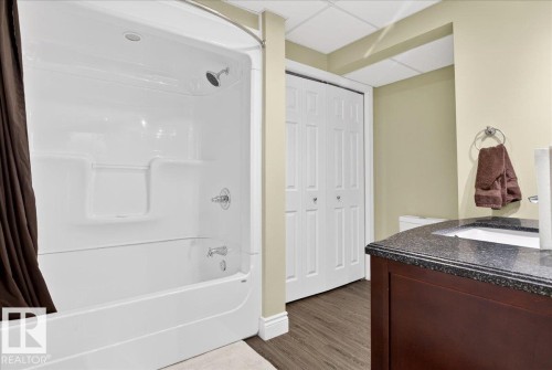 Full bath with vanity, shower / tub combo with curtain, a closet, dark wood-type flooring, and a drop ceiling - 13217 155 Avenue Nw, Edmonton, AB - Indoor Photo Showing Bathroom