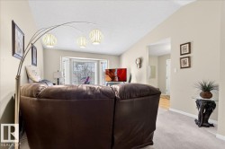 Living area with light colored carpet and a textured ceiling - 