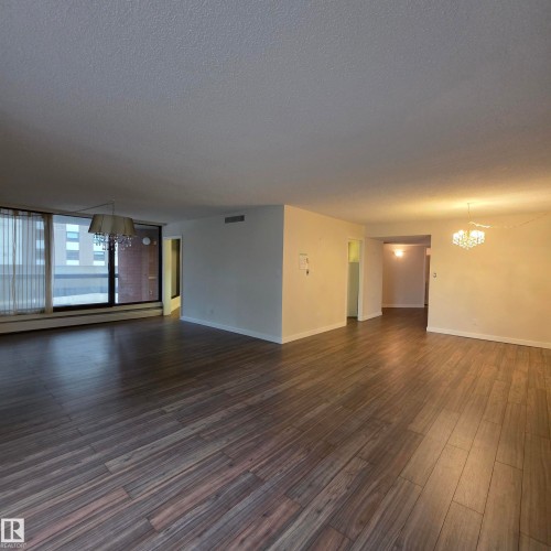 Unfurnished room with suspended lighting, dark wood-type flooring, baseboard heating, and a textured ceiling - 2C 10050 118 Street, Edmonton, AB - Indoor