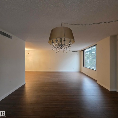 Unfurnished dining area featuring hanging lights, a textured ceiling, and dark wood-style flooring - 2C 10050 118 Street, Edmonton, AB - Indoor Photo Showing Other Room