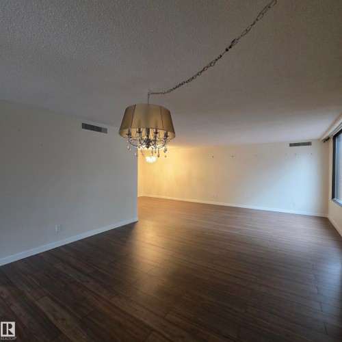 Unfurnished room with a textured ceiling, a chandelier, and dark wood-style floors - 2C 10050 118 Street, Edmonton, AB - Indoor Photo Showing Other Room