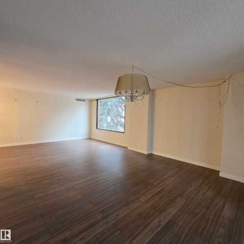 Spare room featuring hanging lights, dark wood finished floors, and a textured ceiling - 2C 10050 118 Street, Edmonton, AB - Indoor Photo Showing Other Room