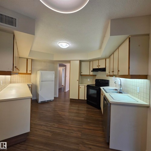 Kitchen with light countertops, tasteful backsplash, freestanding refrigerator, black electric range oven, and a textured ceiling - 2C 10050 118 Street, Edmonton, AB - Indoor Photo Showing Kitchen With Double Sink