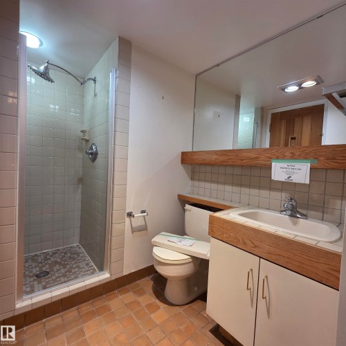 Full bath with a shower stall, decorative backsplash, vanity, and light tile patterned flooring - 2C 10050 118 Street, Edmonton, AB - Indoor Photo Showing Bathroom