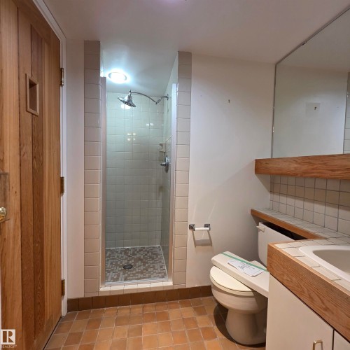 Bathroom with a stall shower, vanity, light tile patterned floors, and decorative backsplash - 2C 10050 118 Street, Edmonton, AB - Indoor Photo Showing Bathroom