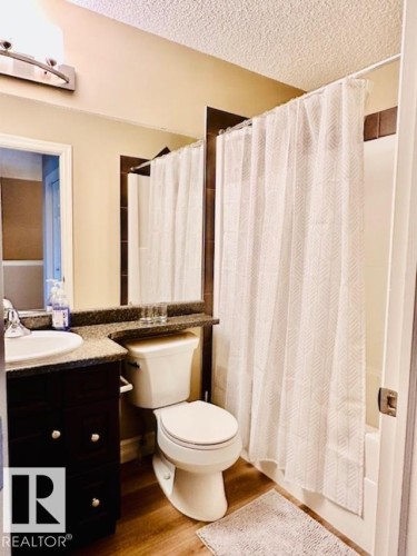 Bathroom featuring vanity, light wood-type flooring, a textured ceiling, and shower / bathtub combination with curtain - 12219 167A Avenue, Edmonton, AB - Indoor Photo Showing Bathroom