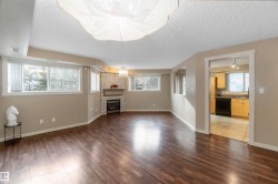Unfurnished living room with dark wood-type flooring, a textured ceiling, and a stone fireplace - 