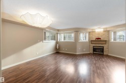 Unfurnished living room with a stone fireplace, dark wood-style floors, a textured ceiling, and plenty of natural light - 