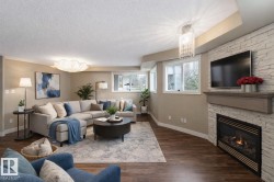 Living area with dark wood-style floors, hanging lights, a fireplace, and a textured ceiling - 