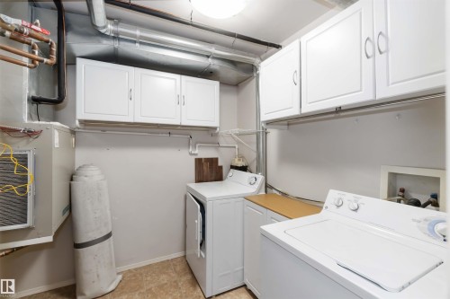Laundry area featuring independent washer and dryer and cabinet space - 113 10311 111 Street, Edmonton, AB - Indoor Photo Showing Laundry Room