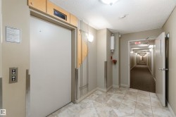 Hallway with a textured ceiling, elevator, and light carpet - 