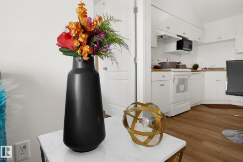 Kitchen featuring white cabinets, white appliances, dark wood-style floors, lofted ceiling, and light countertops - 502 7511 171 Street Nw, Edmonton, AB - Indoor Photo Showing Kitchen
