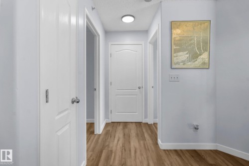 Hallway featuring a textured ceiling and light wood-style floors - 502 7511 171 Street Nw, Edmonton, AB - Indoor Photo Showing Other Room