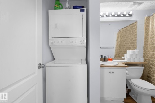 Bathroom with vanity, a shower with shower curtain, and stacked washer and dryer - 502 7511 171 Street Nw, Edmonton, AB - Indoor Photo Showing Laundry Room