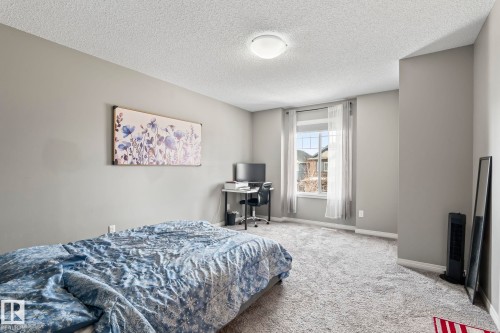 Carpeted bedroom with a desk and a textured ceiling - 3221 Cherry Cres Sw, Edmonton, AB - Indoor Photo Showing Bedroom