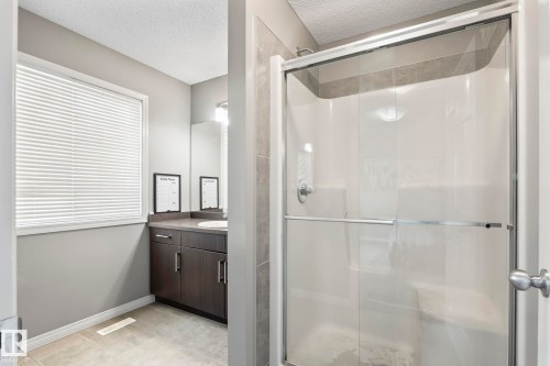 Bathroom with a stall shower, vanity, a textured ceiling, and light tile patterned floors - 3221 Cherry Cres Sw, Edmonton, AB - Indoor Photo Showing Bathroom
