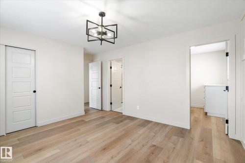 Unfurnished bedroom with light wood-style floors, suspended lighting, and a closet - 4120 108 Street, Edmonton, AB - Indoor Photo Showing Other Room