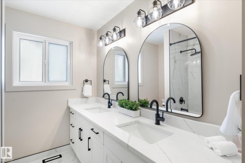 Bathroom featuring a marble finish shower, double vanity, plenty of natural light, and light marble finish floors - 4120 108 Street, Edmonton, AB - Indoor Photo Showing Bathroom