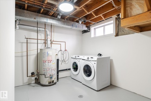 Laundry area featuring finished concrete flooring, gas water heater, and washing machine and dryer - 4120 108 Street, Edmonton, AB - Indoor Photo Showing Laundry Room