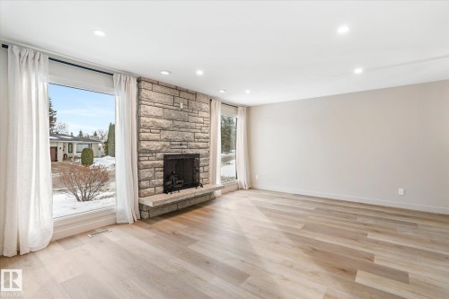 Unfurnished living room with light wood-style flooring, a stone fireplace, and recessed lighting - 4120 108 Street, Edmonton, AB - Indoor Photo Showing Living Room With Fireplace