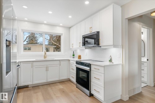 Kitchen with stainless steel appliances, light wood-style flooring, light stone counters, white cabinetry, and recessed lighting - 4120 108 Street, Edmonton, AB - Indoor Photo Showing Kitchen With Upgraded Kitchen