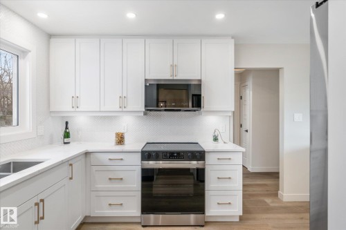 Kitchen featuring electric stove, white cabinetry, light stone counters, stainless steel microwave, and recessed lighting - 4120 108 Street, Edmonton, AB - Indoor Photo Showing Kitchen With Upgraded Kitchen