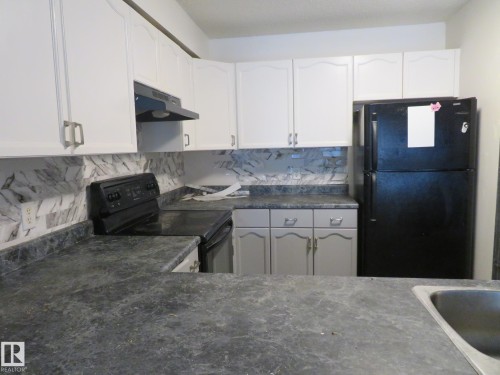 Kitchen with dark countertops, black appliances, decorative backsplash, and white cabinetry - 2945 26 Street, Edmonton, AB - Indoor Photo Showing Kitchen