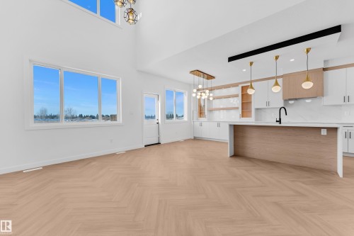 Unfurnished living room with hanging lights, parquet floors, and a high ceiling - 38 Grayson Green, Stony Plain, AB - Indoor Photo Showing Kitchen