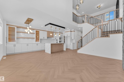 Kitchen featuring white cabinets, open floor plan, a chandelier, parquet flooring, and a high ceiling - 38 Grayson Green, Stony Plain, AB - Indoor Photo Showing Kitchen